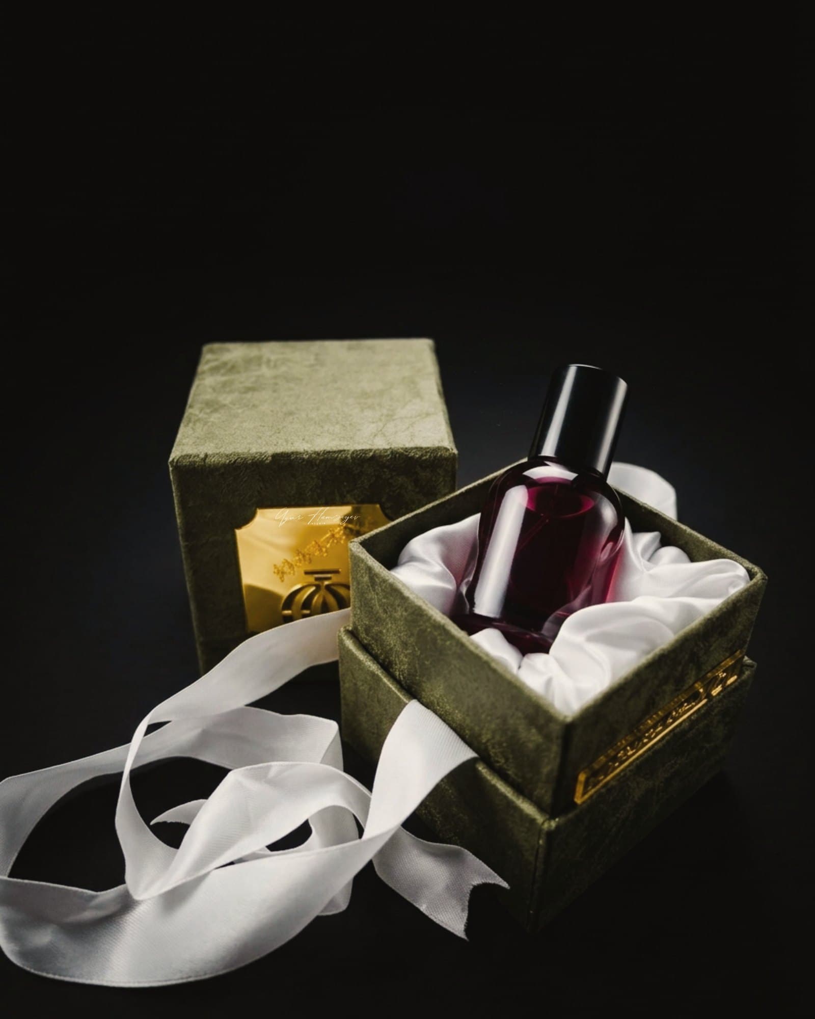 Perfume bottle in an open rigid gift box with satin ribbon
