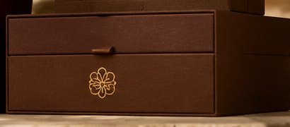 Brown drawer box with a small leather pull and gold foil emblem